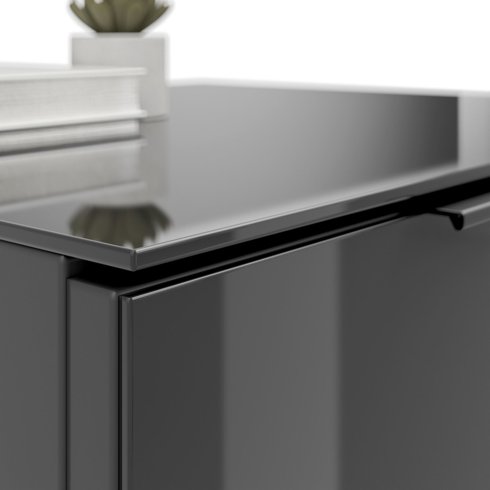 Nahaufnahme einer modernen, glänzenden Nachtkommode in dunkler Farbe mit einer Pflanze und Büchern darauf, aus seitlicher Perspektive.