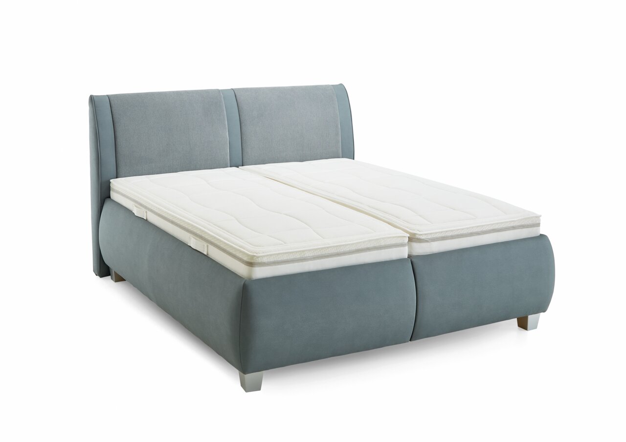 Stoffen bed in lichtblauwe stof met twee witte matrasbeschermers, zijaanzicht