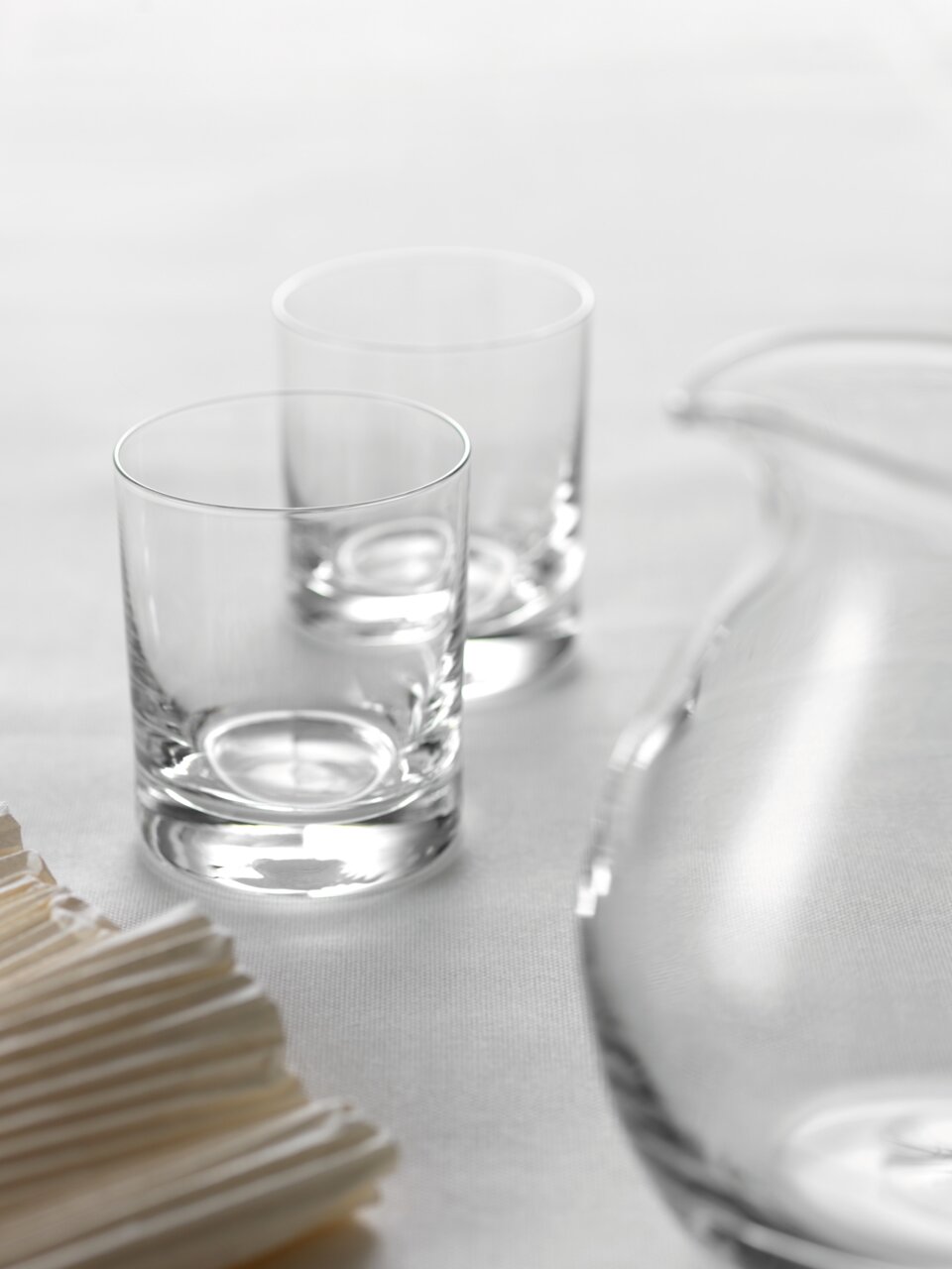Zwei klare Trinkgläser Easy+ 310ml auf einem weißen Tisch, seitliche Perspektive.