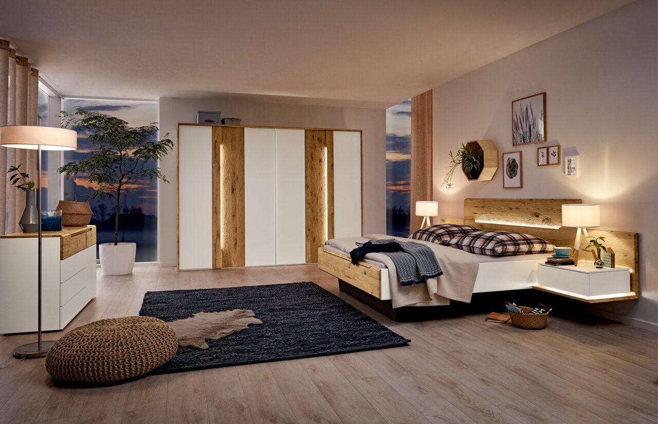 Komfortbett in modernem Schlafzimmer mit Holz- und Weißtönen, seitliche Perspektive