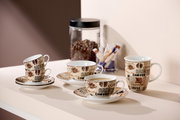 Vier Kaffeetassen mit Untertassen, dekoriert mit Kaffeebohnen- und Schriftmotiven, auf einem Tisch arrangiert. Im Hintergrund ein Glasbehälter mit Kaffeebohnen und Zuckersticks. Perspektive von schräg oben.