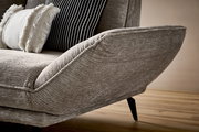 Nahaufnahme eines modernen Longchairs mit grauem Stoffbezug und dekorativen Kissen, seitliche Perspektive.
