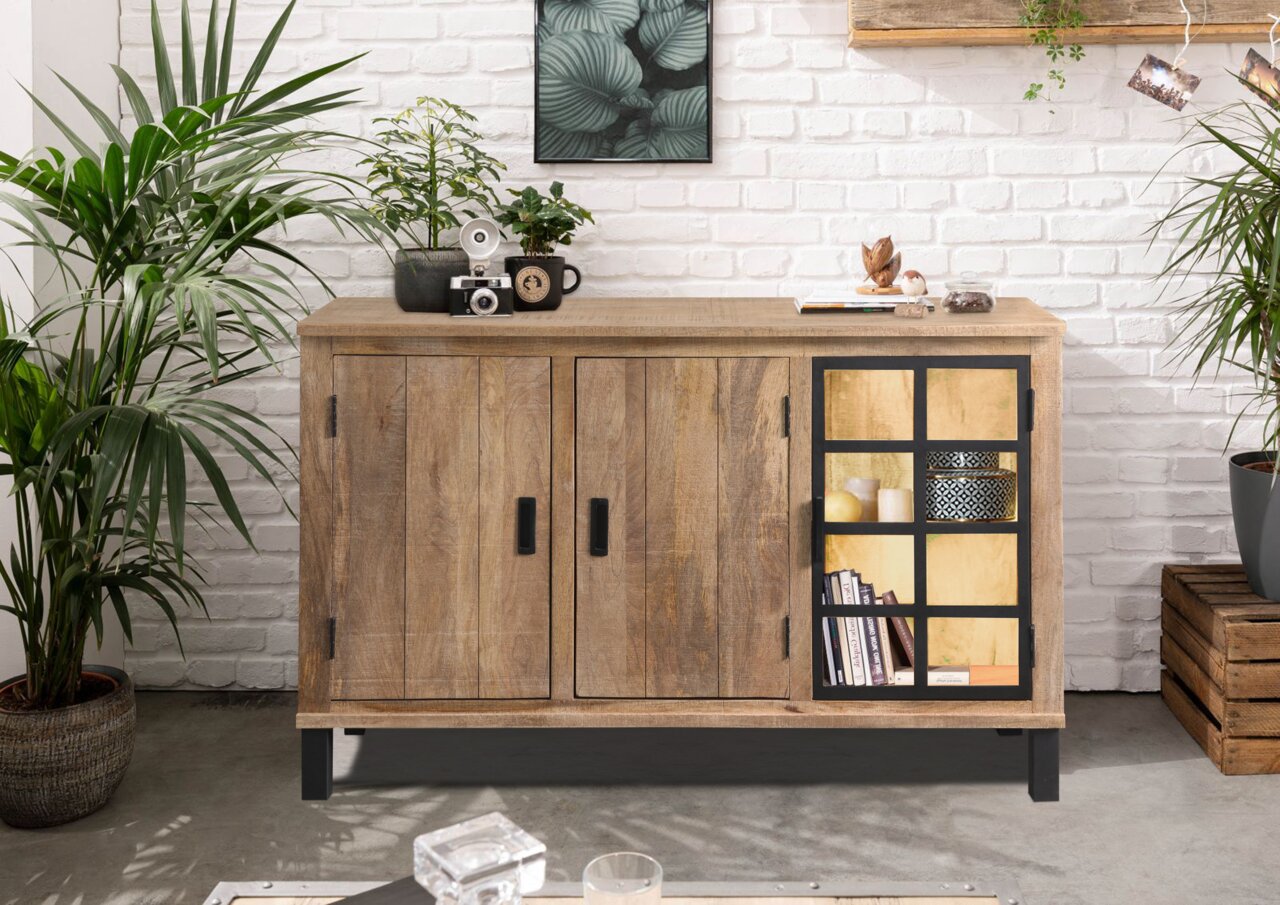Frontale Ansicht des Sideboards KALI aus Holz mit zwei Türen und einem Regal mit Glastür, dekoriert mit Pflanzen und Accessoires.