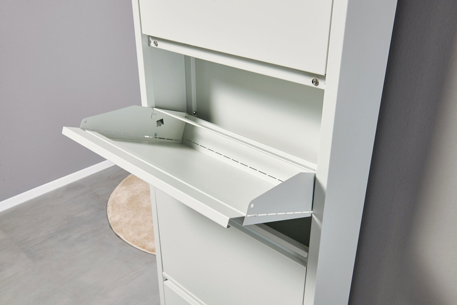 Weißer Metallschrank mit ausgeklappter Klappe/Ablagefläche, Detailansicht aus schräger Seitenperspektive von vorn