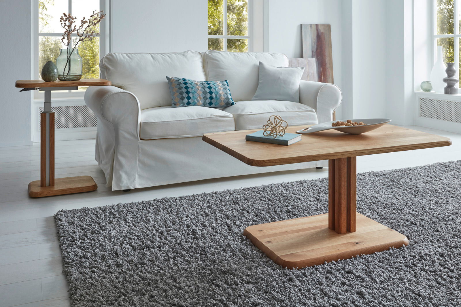 Moderner Couchtisch aus Holz in einem hellen Wohnzimmer, frontal fotografiert, mit einem weißen Sofa im Hintergrund.
