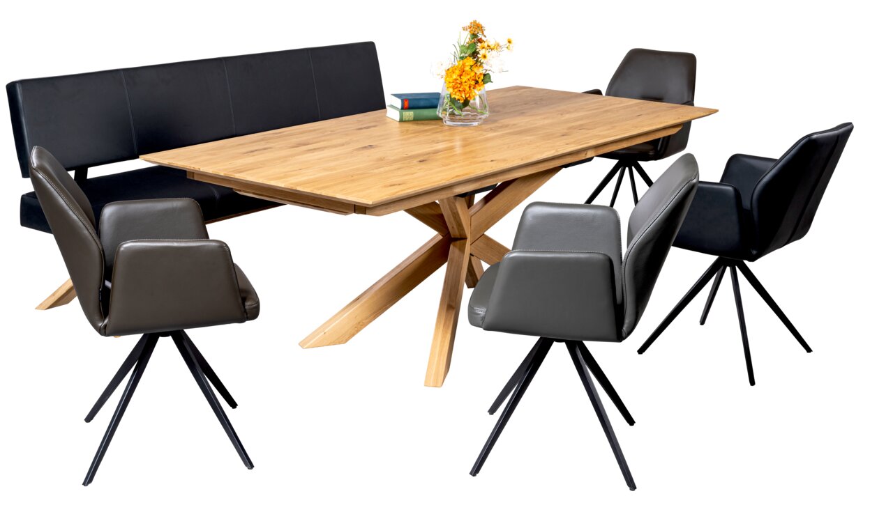 Linea Natura Esstisch FRANK Moderner Esstisch aus Holz mit X-förmigem Gestell, umgeben von schwarzen Stühlen und einer Bank, seitliche Perspektive.