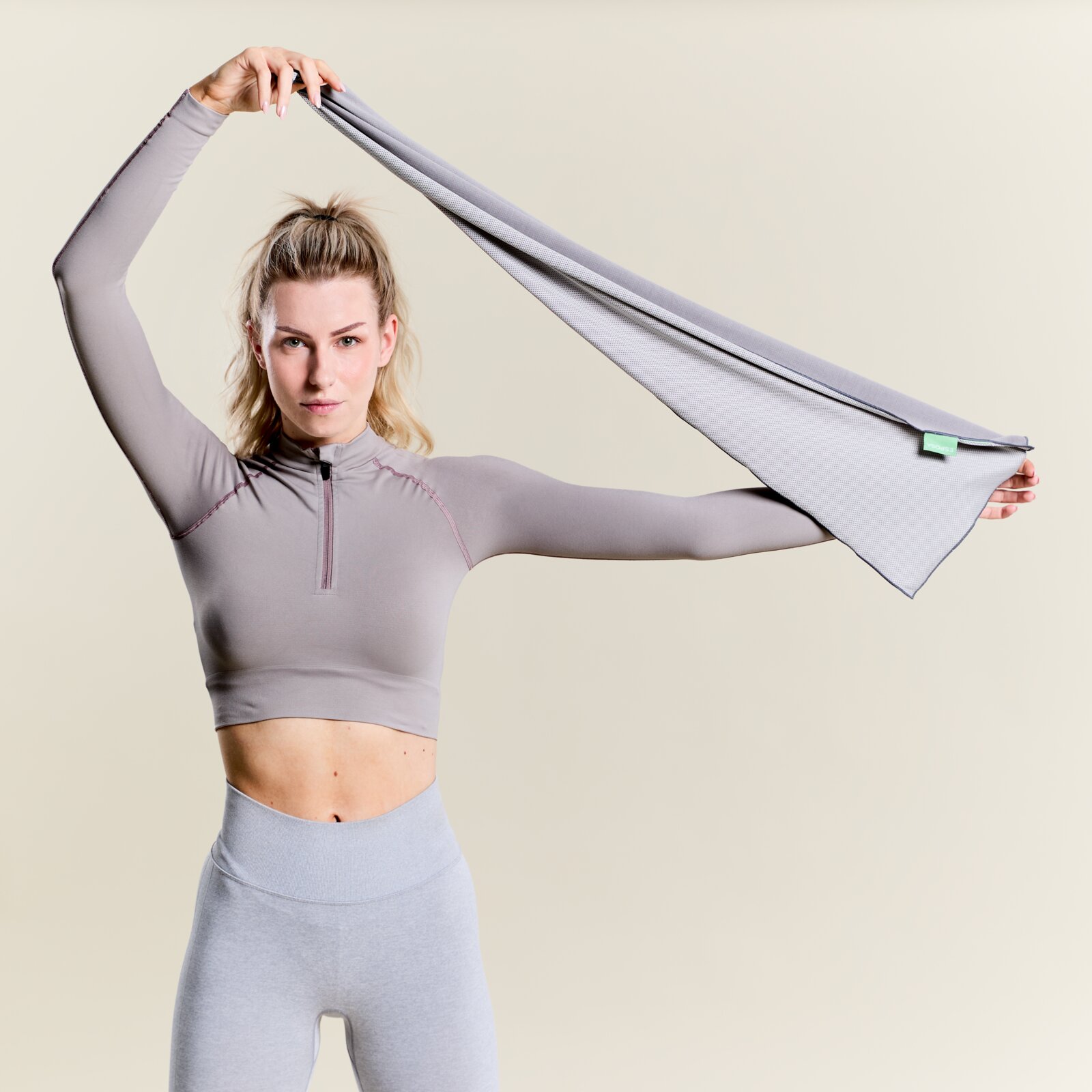 Vrouw in sportkleding houdt een grijze sporthanddoek omhoog, frontale weergave