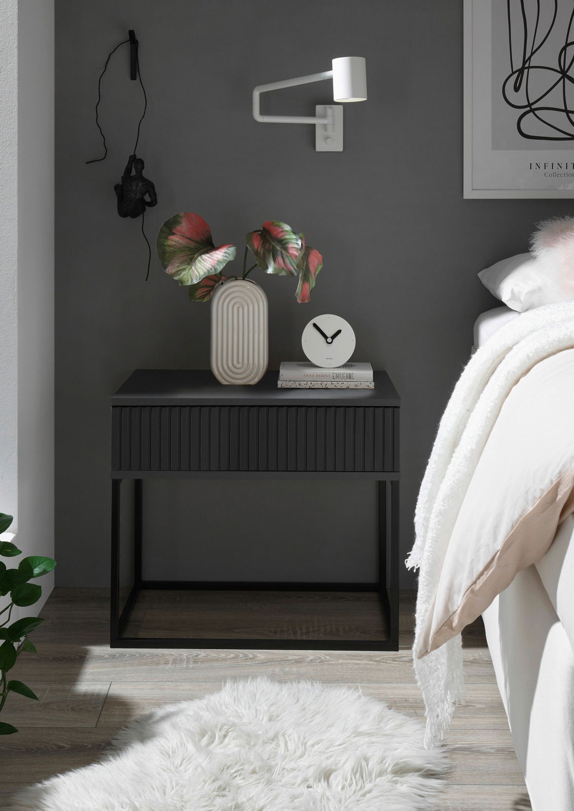 Moderne Nachtkommode in dunklem Design mit dekorativer Vase und Uhr, seitliche Perspektive