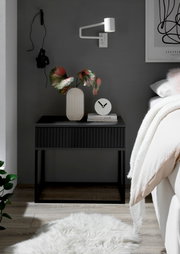 Moderne Nachtkommode in dunklem Design mit dekorativer Vase und Uhr, seitliche Perspektive