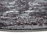 Nahaufnahme eines Designer-Teppichs mit abstraktem Muster in Grau- und Rottönen, seitliche Perspektive.