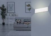 Moderne weiße Aluminium-Wandleuchte in einem stilvoll eingerichteten Wohnzimmer, seitliche Perspektive.