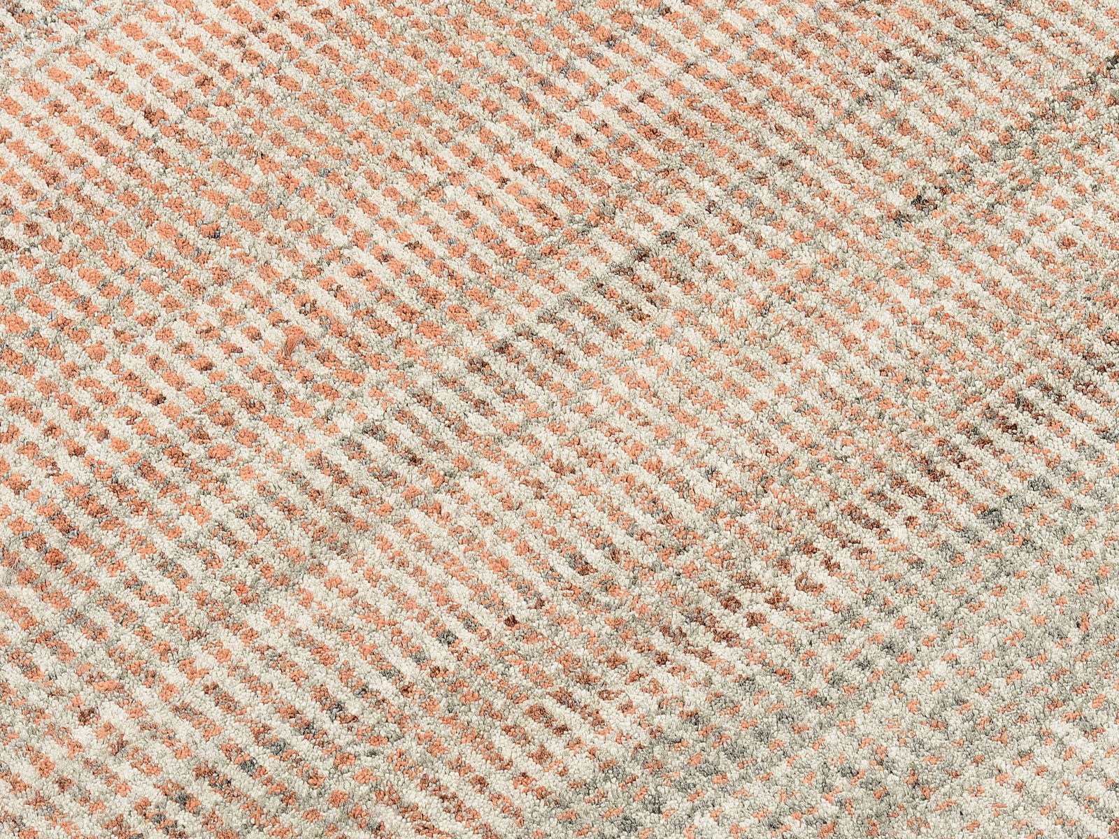 Nahaufnahme eines Designer Teppichs mit diagonalen Streifen in Beige- und Rottönen.