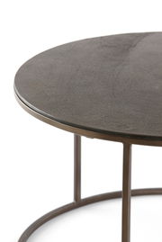 Nahaufnahme eines runden Couchtisches mit dunkler Tischplatte und Metallgestell, seitliche Perspektive.