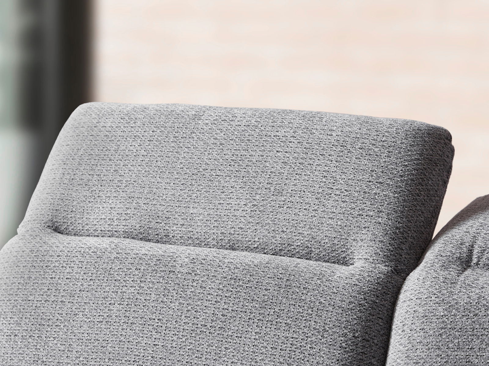 Nahaufnahme einer grauen Longchairkombination mit texturierter Oberfläche, seitliche Perspektive.
