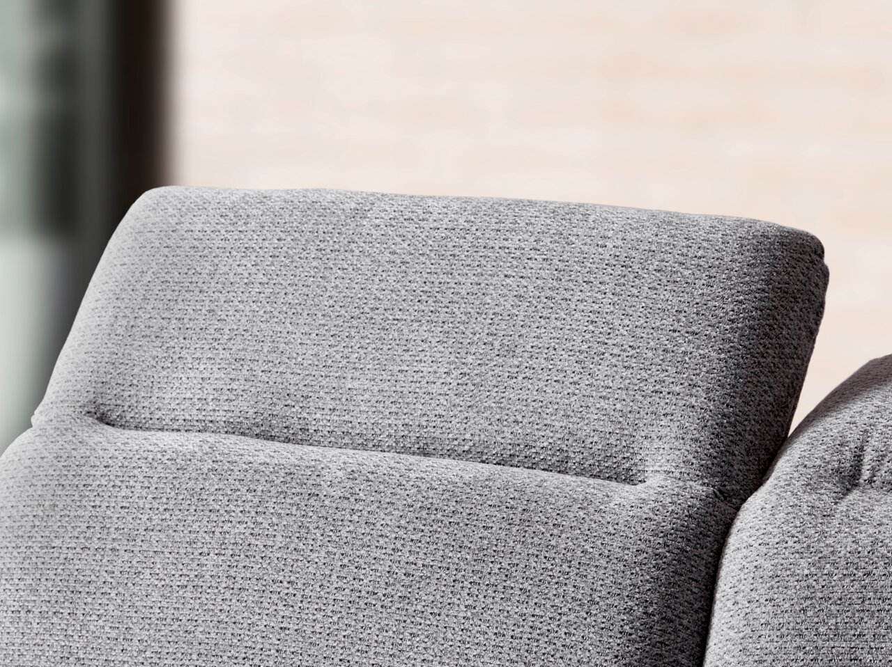 Close-up van een grijze longchair-set met een gestructureerd oppervlak, gezien vanaf de zijkant.