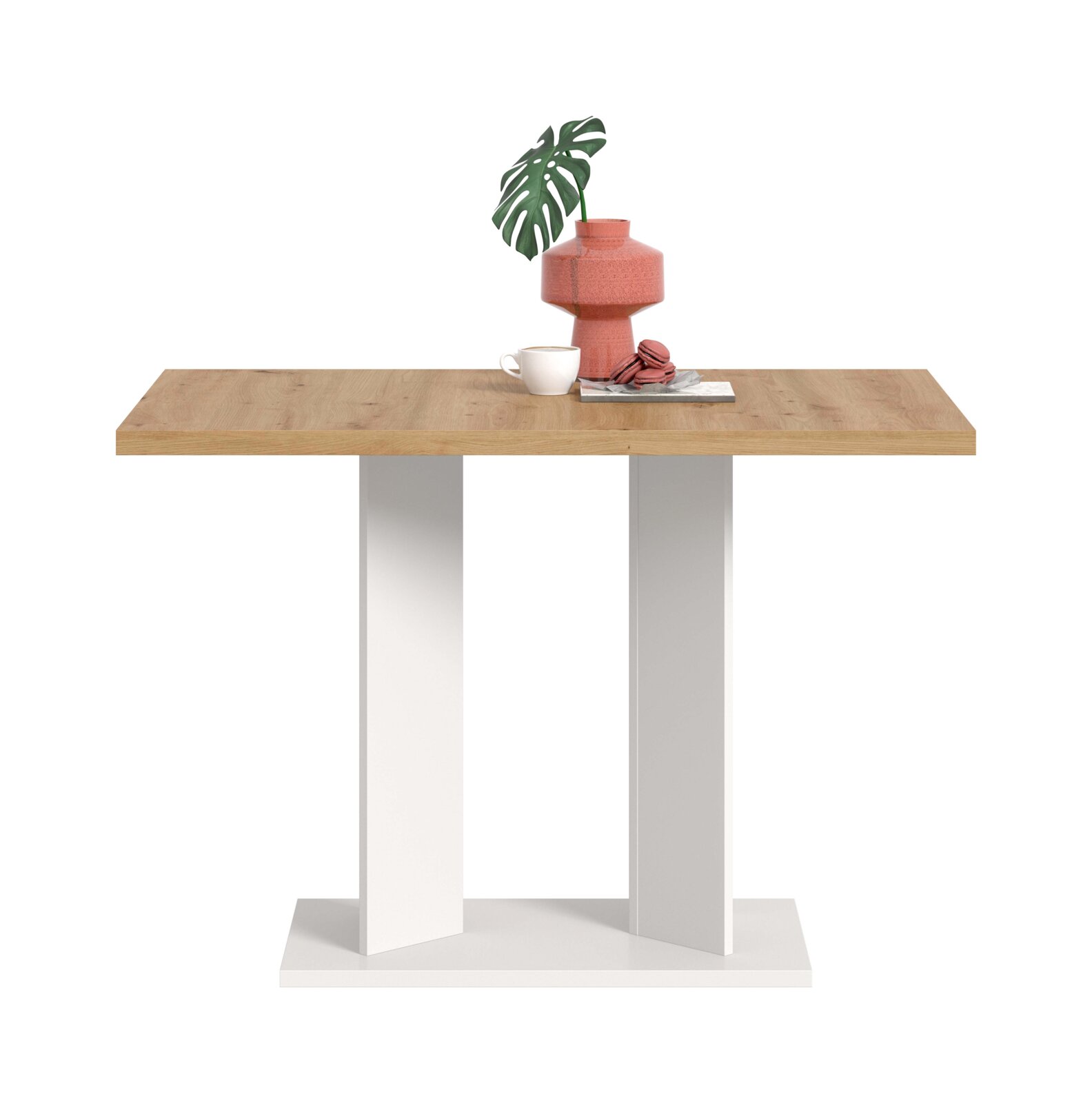 Moderner Esstisch mit rechteckiger Holzplatte und weißem, kreuzförmigem Gestell, frontal aus leichter Aufsicht fotografiert; auf der Platte Vase mit Monstera-Blatt, Tasse und Macarons auf einem Buch vor weißem Hintergrund.