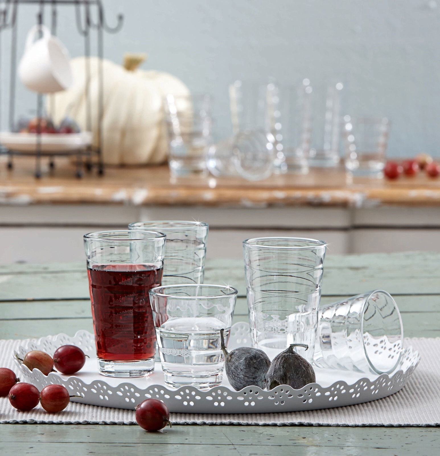 Becherset Wave 12-tlg. auf einem dekorativen Tablett, mit verschiedenen Gläsern, gefüllt mit Wasser und Saft, aus der Seitenperspektive fotografiert.