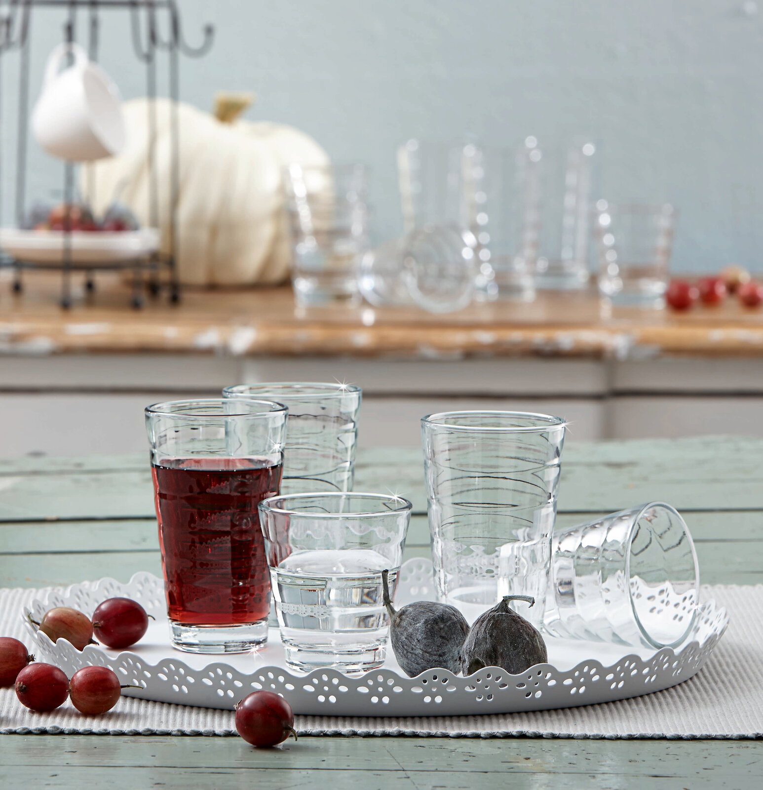 Becherset Wave 12-tlg. auf einem dekorativen Tablett, mit verschiedenen Gläsern, gefüllt mit Wasser und Saft, aus der Seitenperspektive fotografiert.