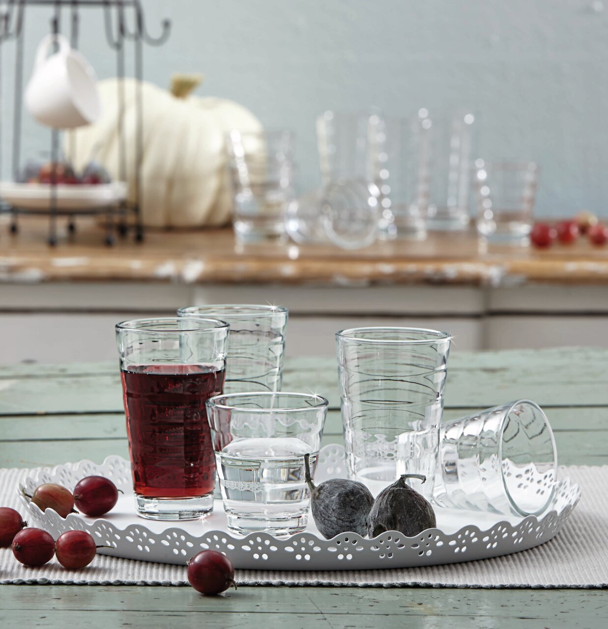 Becherset Wave 12-tlg. auf einem dekorativen Tablett, mit verschiedenen Gläsern, gefüllt mit Wasser und Saft, aus der Seitenperspektive fotografiert.