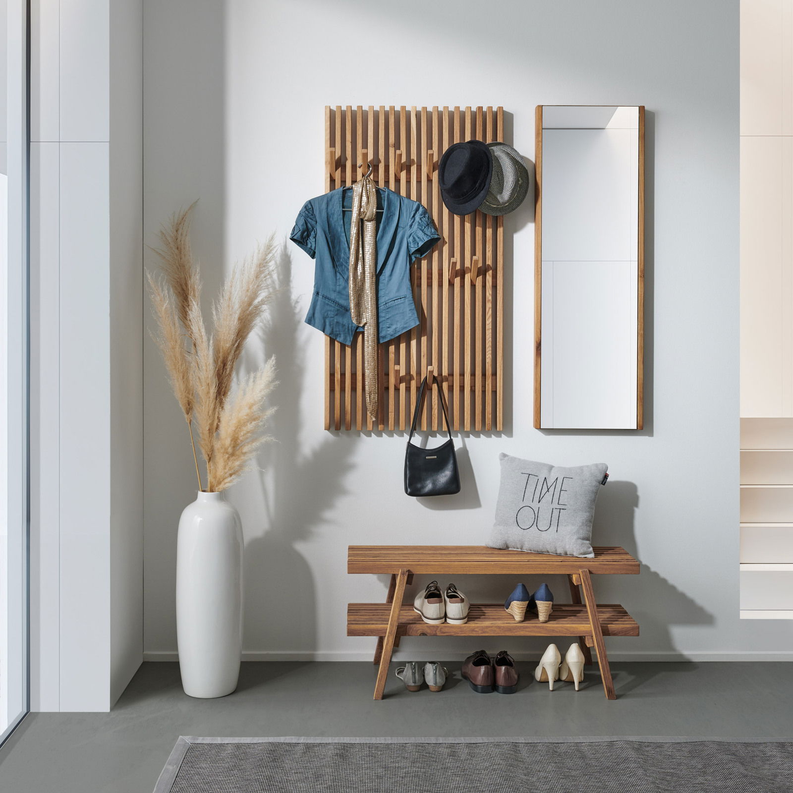 Garderoben-Set mit Holzpaneel, Spiegel und Bank, frontal fotografiert. Dekoriert mit Hüten, Jacke, Tasche und Schuhen.