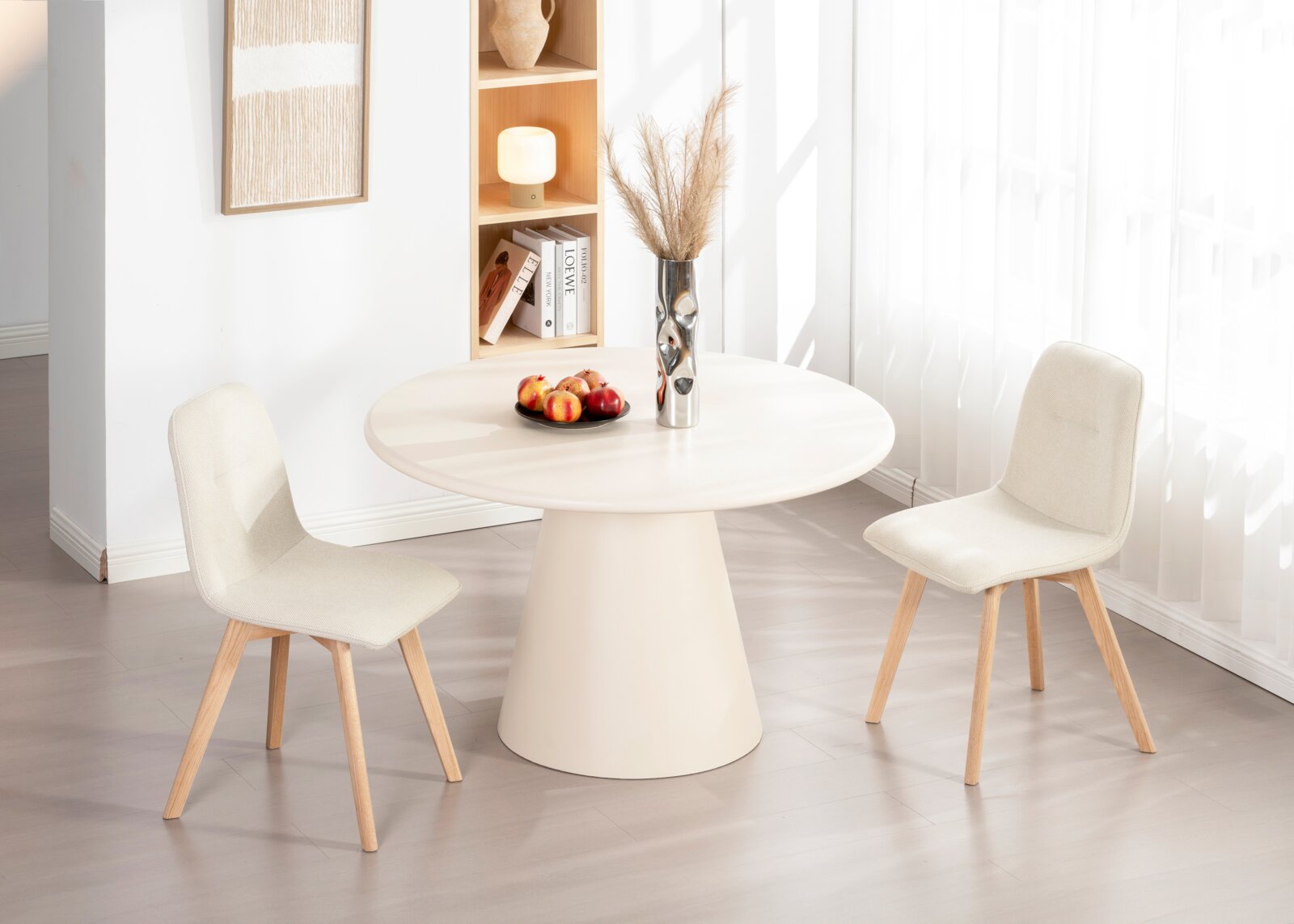 Zwei moderne, cremefarbene Stühle mit Holzbeinen stehen um einen runden, weißen Tisch in einem hellen Raum. Perspektive: seitlich.