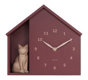 Wanduhr in Form eines Hauses mit einer kleinen Katzenfigur auf der linken Seite, frontal betrachtet.