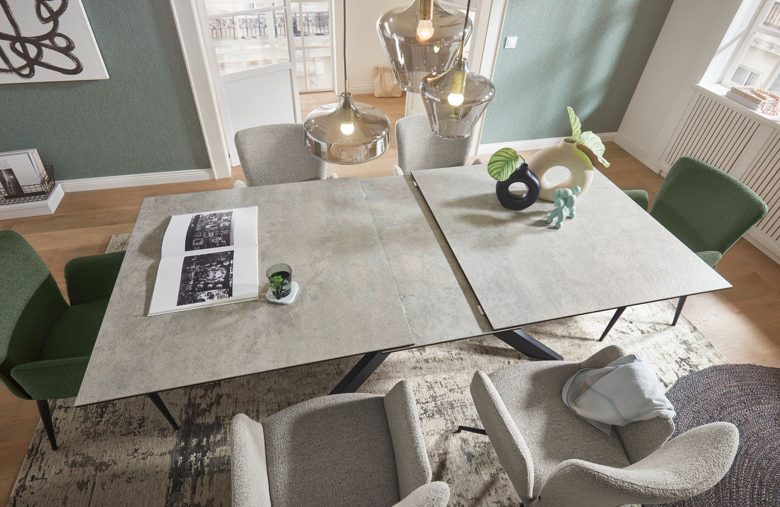 Moderner Esstisch mit erweiterbarer Tischplatte, umgeben von stilvollen Stühlen in einem eleganten Esszimmer, aus der Vogelperspektive fotografiert.