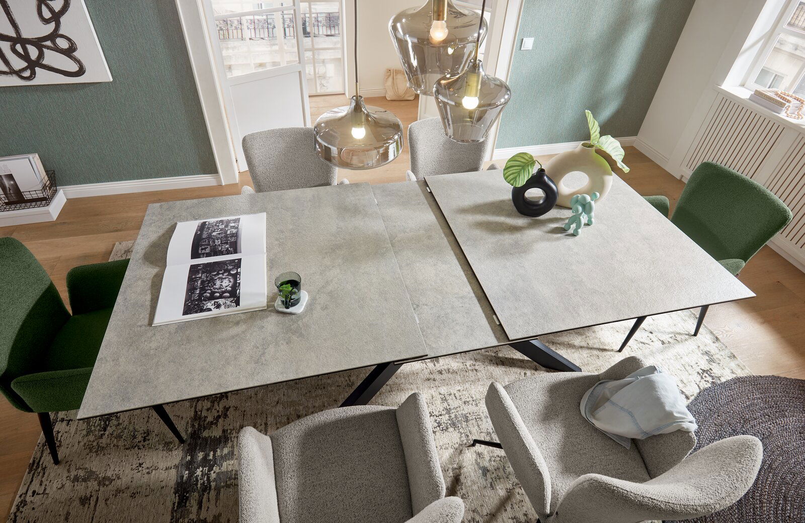 Moderner Esstisch mit erweiterbarer Tischplatte, umgeben von stilvollen Stühlen in einem eleganten Esszimmer, aus der Vogelperspektive fotografiert.