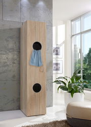 Moderner Wäscheschrank aus Holz mit runden Öffnungen, seitliche Perspektive, in einem hellen Raum mit großen Fenstern.