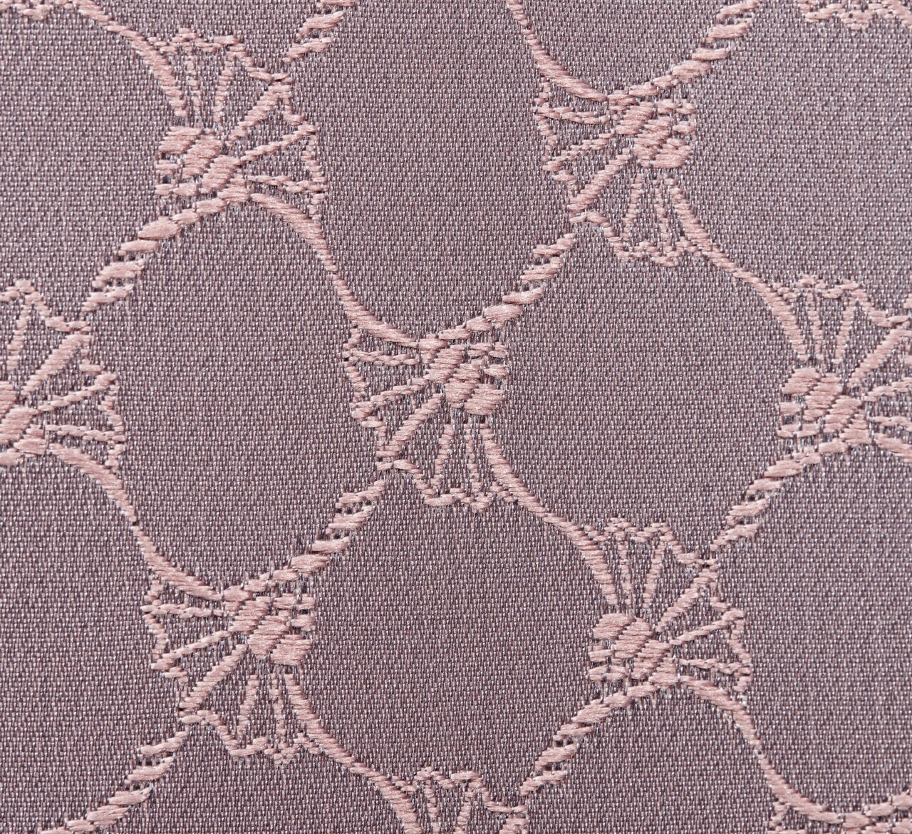 Nahaufnahme eines Stoffes mit einem eleganten, kreisförmigen Muster in Nude-Tönen.