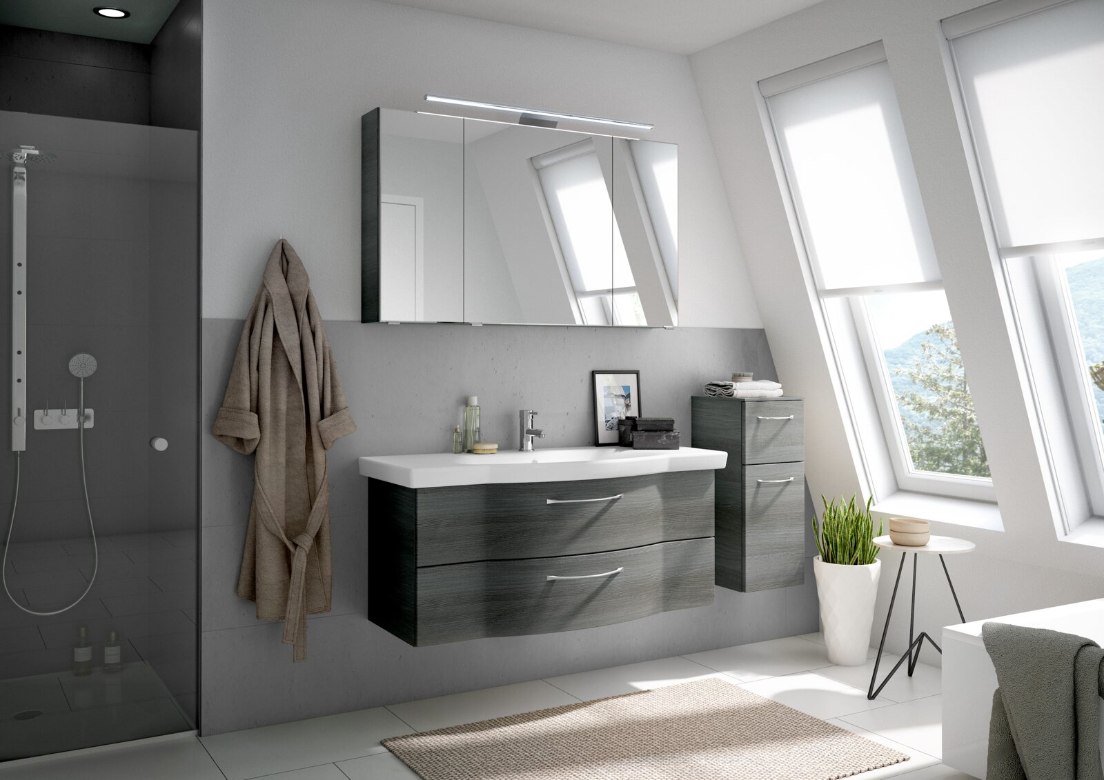 Moderne Badezimmermöbel in einem hellen Raum mit schrägen Fenstern, bestehend aus einem hängenden Waschtisch mit zwei Schubladen und einem Spiegelschrank darüber, seitlich ein hoher Schrank. Perspektive von vorne.