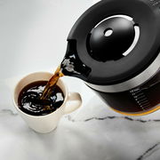 Kaffeemaschine in onyx schwarz gießt Kaffee in eine Tasse, seitliche Perspektive