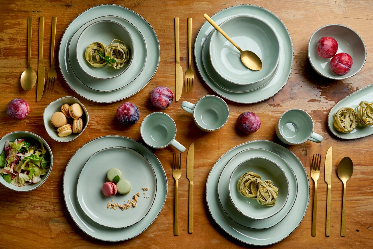 Kombiservice Urban 16-tlg. von Van Well in einer stilvollen Tischdekoration mit goldfarbenem Besteck, aus der Vogelperspektive fotografiert.