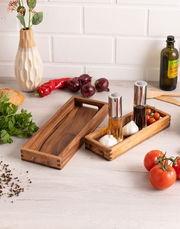 Längliches Servier-Tablett aus Holz, von oben fotografiert, umgeben von frischen Zutaten wie Tomaten, Knoblauch und Kräutern.