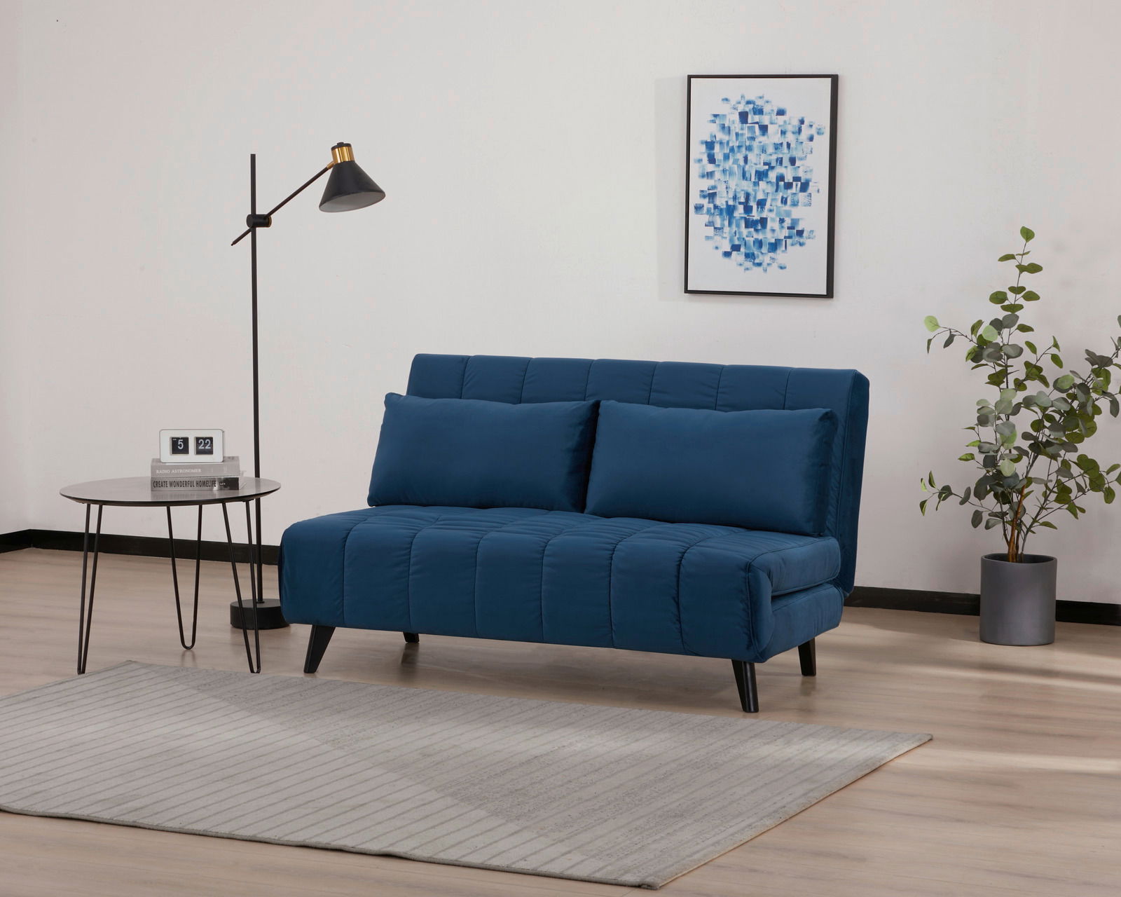 Blaues Funktionssofa in modernem Wohnzimmer, seitliche Perspektive, mit Stehlampe, Beistelltisch und Pflanzen.