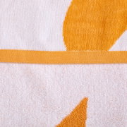 Nahaufnahme (Detailansicht von oben) eines weißen Frottee-Handtuchs mit orangefarbenem Muster und orangefarbener Bordüre