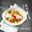 Pastaschale mit Spaghetti, Kirschtomaten, Mozzarella und geriebenem Käse, von oben fotografiert, auf einem Tisch mit Serviette und Vapiano-Logo.