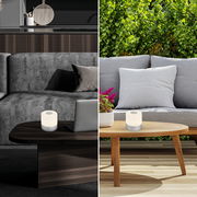 Akku LED Tischleuchte in modernem Design, präsentiert in einem Innenraum auf einem dunklen Holztisch und in einem Außenbereich auf einem hellen Holztisch.