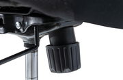 Nahaufnahme der Unterseite eines Drehstuhls mit Fokus auf den Mechanismus und Einstellknopf.