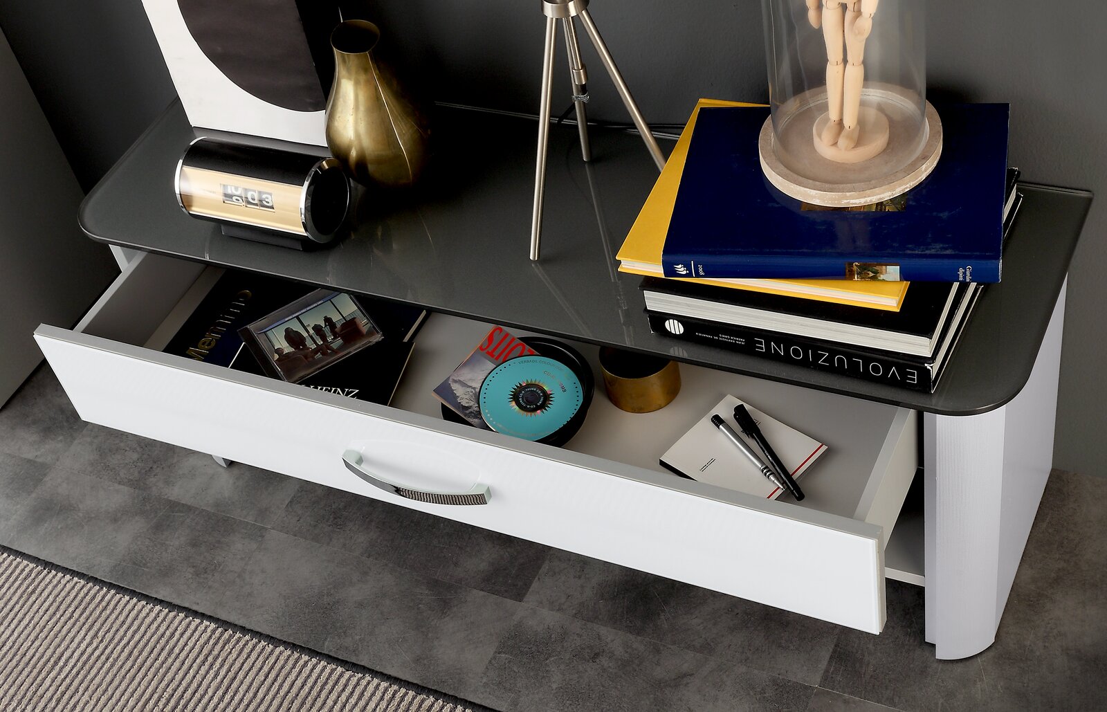 Moderne Bank mit offener Schublade, von oben fotografiert, mit Büchern, einer Uhr und Dekorationen auf der Oberfläche.