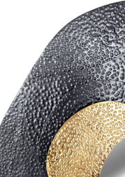 Nahaufnahme eines Spiegels mit strukturiertem, geschwungenem Rahmen in Schwarz und Gold.