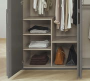 Geöffneter Drehtürenschrank mit sechs Türen, zeigt Innenansicht mit Regalen, hängender Kleidung und Taschen, Perspektive von vorne.