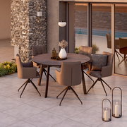 Moderner runder Gartentisch mit vier gepolsterten Stühlen auf einer Terrasse, umgeben von stilvoller Dekoration und Pflanzen, seitliche Perspektive.