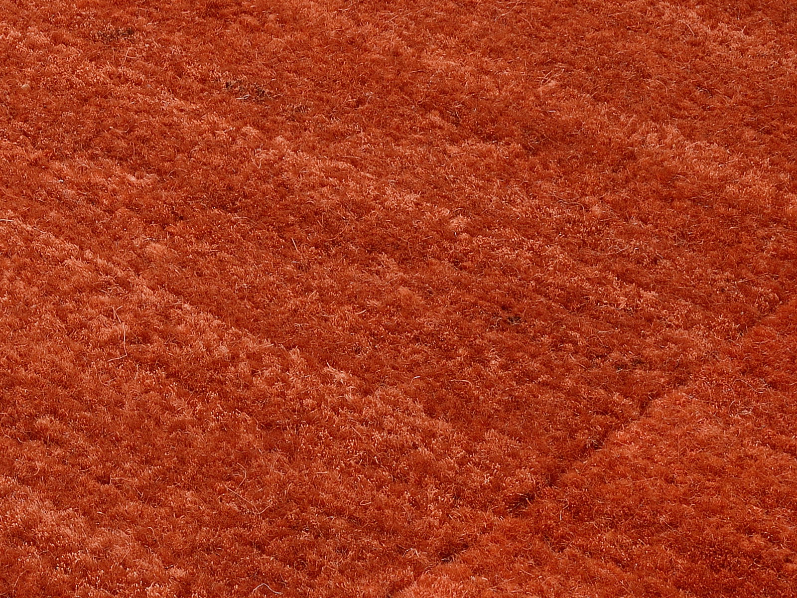Nahaufnahme eines roten Wollteppichs mit weicher Textur und diagonalen Mustern.