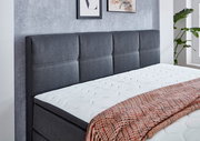 Boxspringbett mit grauem Kopfteil und weißer Matratze, seitliche Perspektive