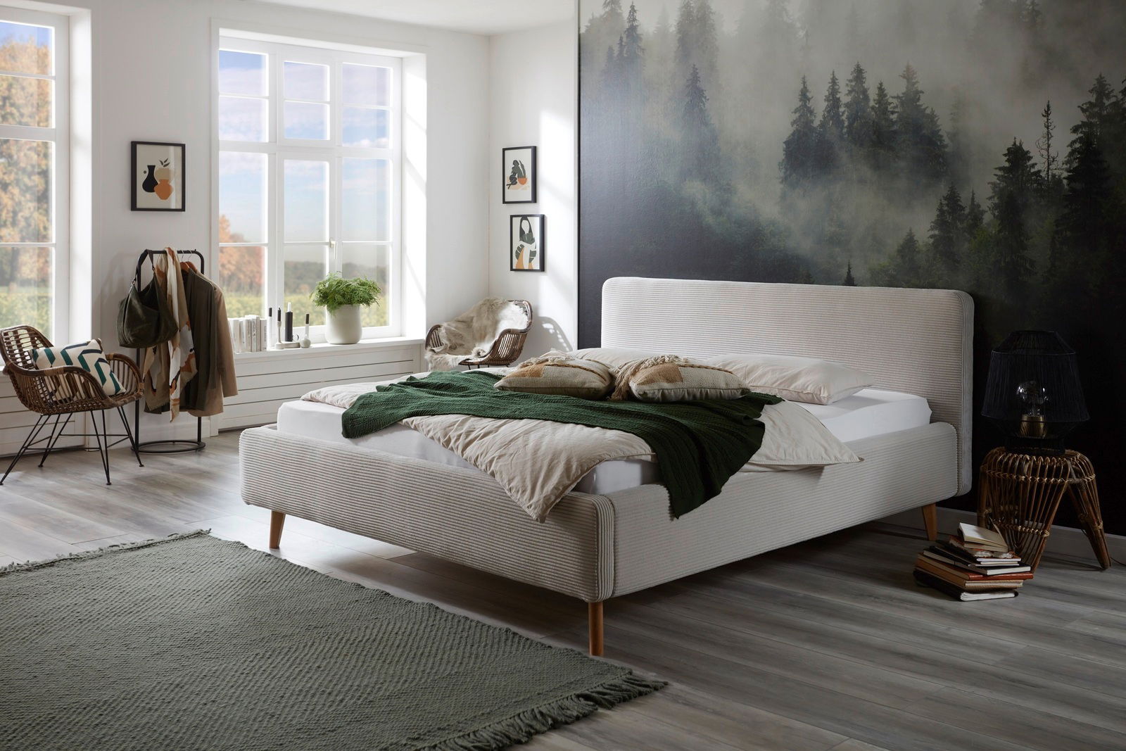 Modernes Polsterbettgestell in einem stilvoll eingerichteten Schlafzimmer mit Waldtapete im Hintergrund, seitliche Perspektive.