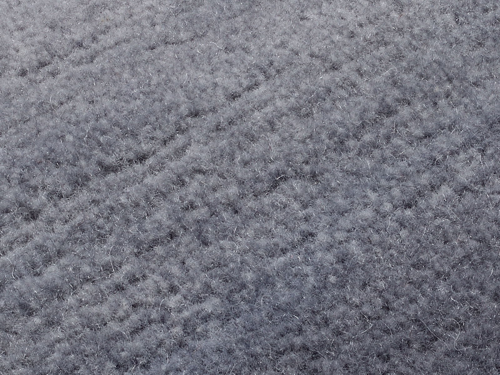 Nahaufnahme eines grauen Wollteppichs mit weicher, flauschiger Textur.
