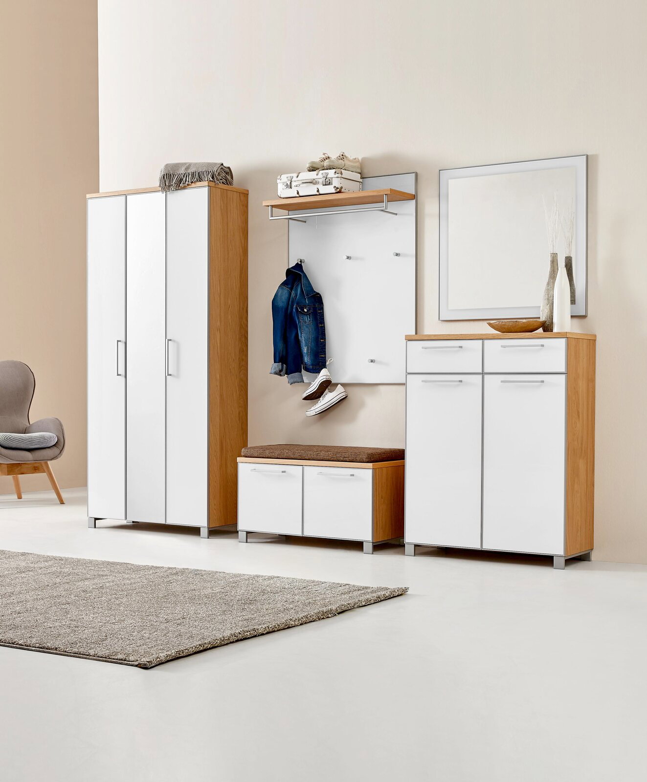 Moderne Garderobenkombination mit weißem und holzfarbenem Finish, bestehend aus einem XL-Dielenschrank, einem Schuhschrank, einem Garderobenpaneel mit Ablage und Haken, einer Sitzbank mit Kissen und einem Spiegel, seitliche Perspektive.