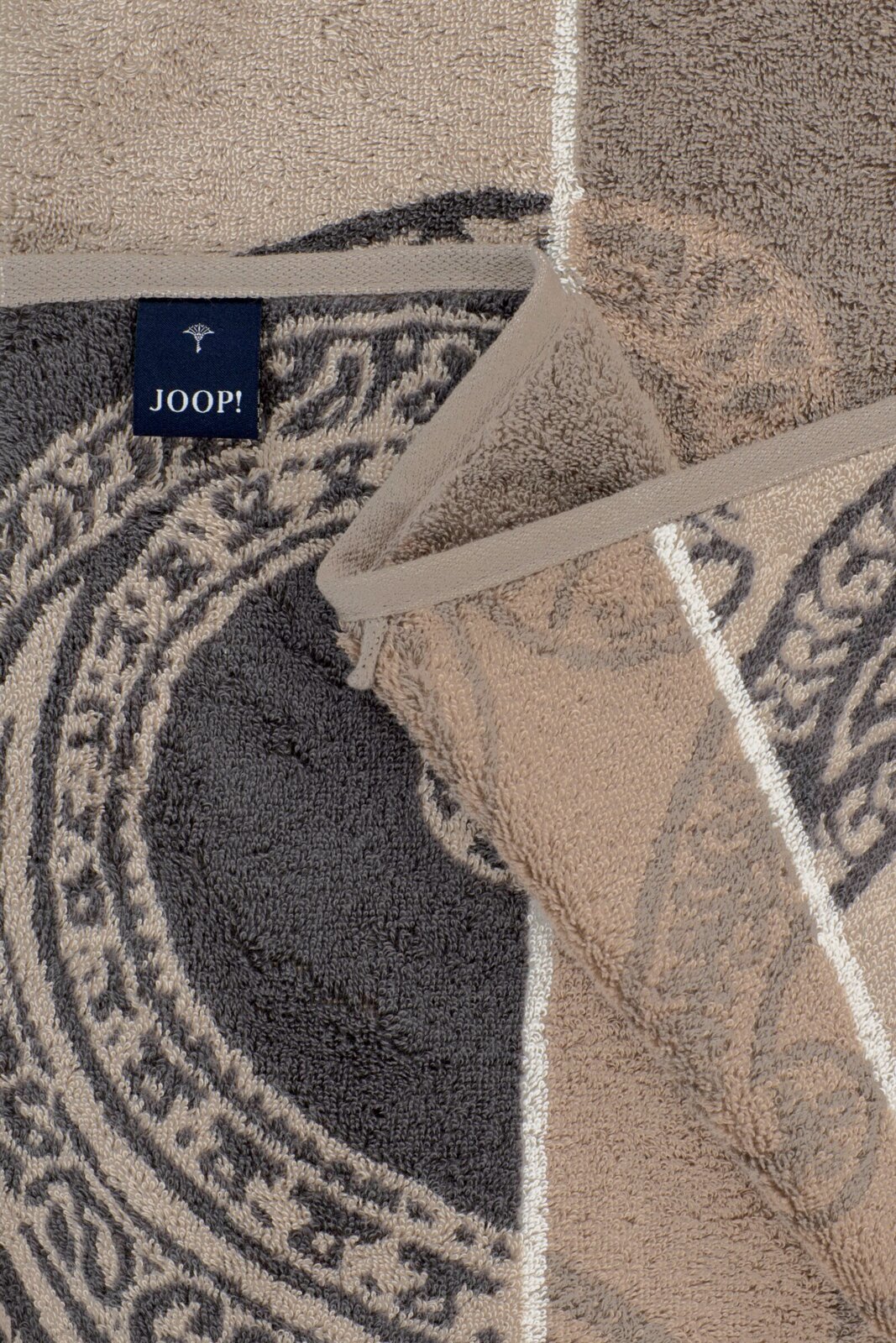 Detailaufnahme aus schräger Nahsicht: JOOP! Frottier-Handtücher in Grau und Beige mit ornamentalem Muster und gewebter Bordüre, übereinandergelegt
