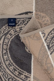 Detailaufnahme aus schräger Nahsicht: JOOP! Frottier-Handtücher in Grau und Beige mit ornamentalem Muster und gewebter Bordüre, übereinandergelegt